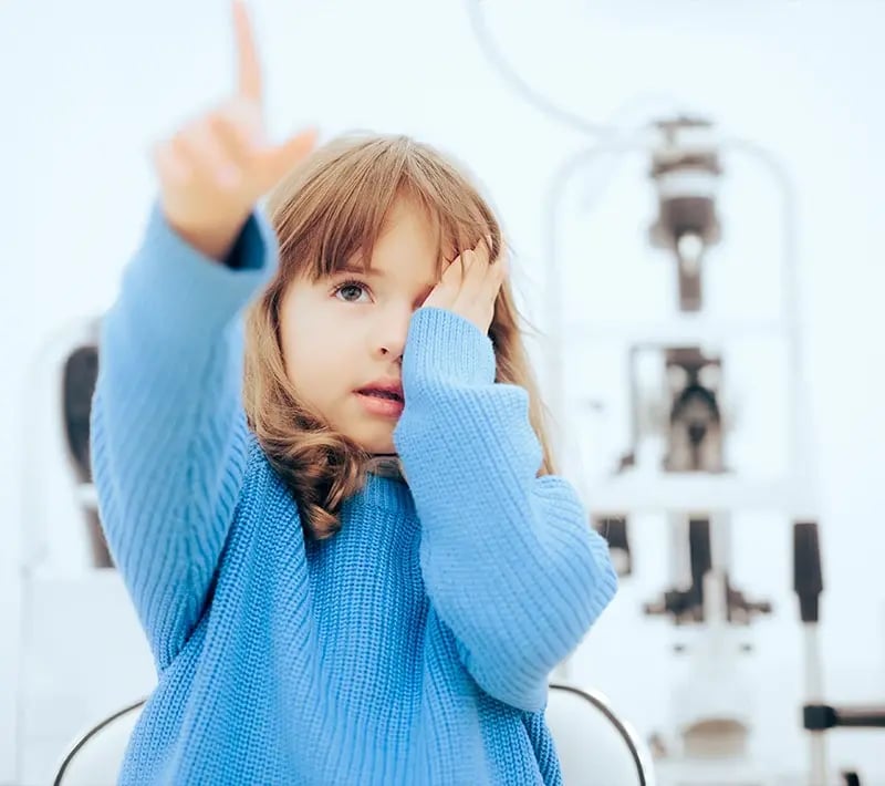 little girl in blue sweater taking vision test
